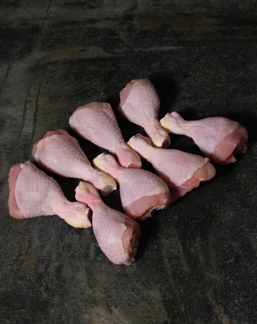 Chicken Drumsticks vom deutschen Hähnchen, auf Schneidebrett mit Kräutern